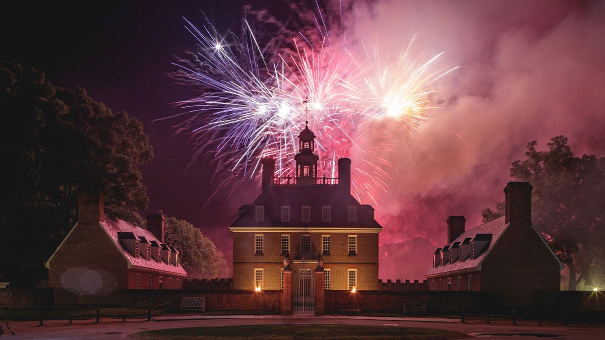 colorful fireworks over historical building surrounded by trees at Lights of Freedom event in Williamsburg, Virginia, USA